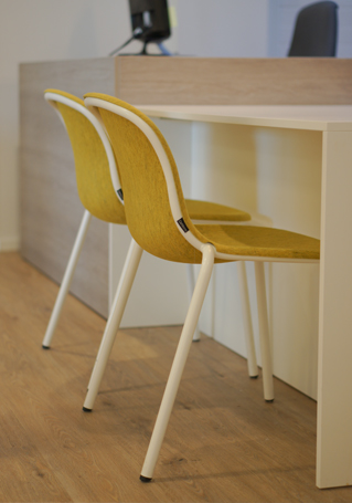Wachtkamer inrichting met gekleurde stoelen en licht houten balie